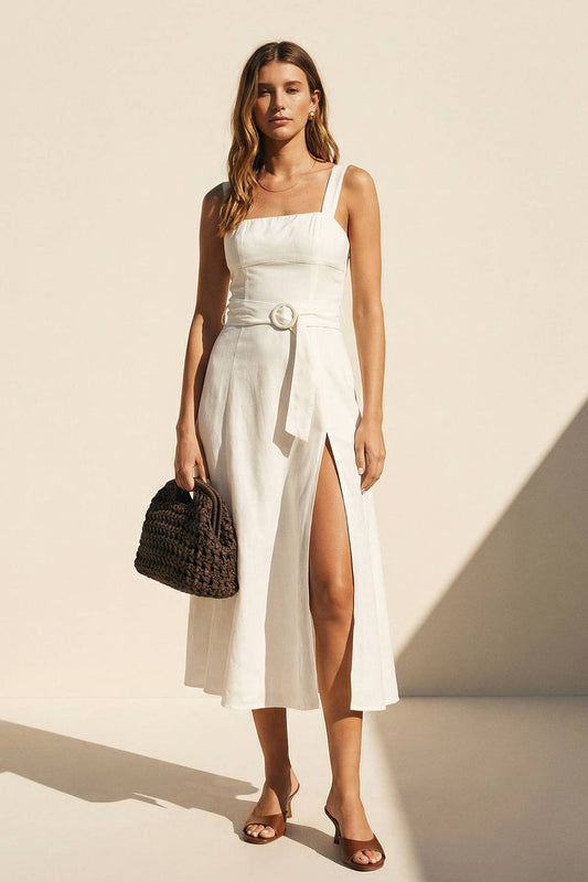 Woman wearing a white dress with a black handbag on a beige background