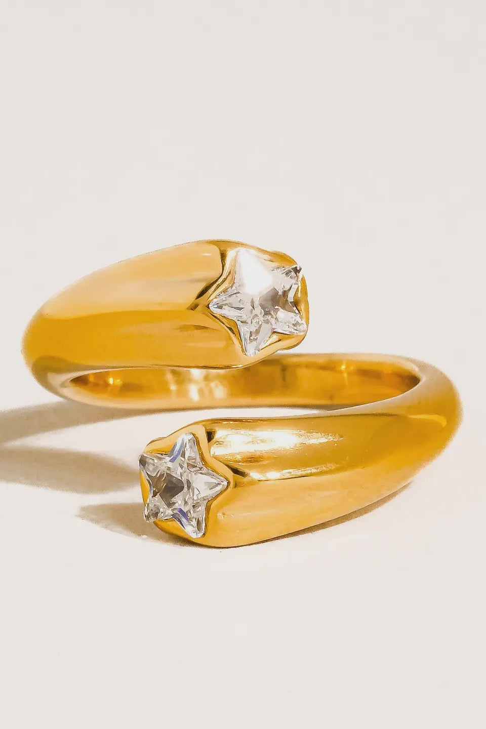 Gold ring with diamond-like stones on a light beige background