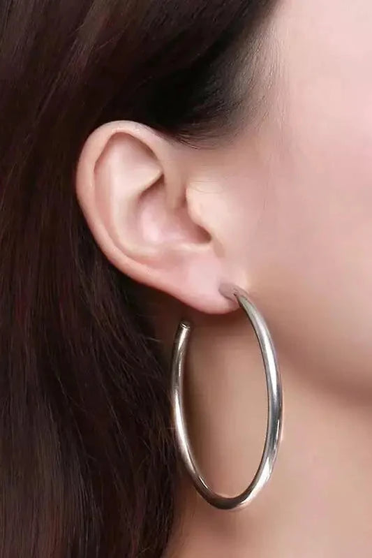 Silver hoop earring worn by a person with dark hair.