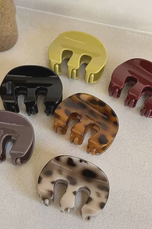 Set of eight hair clips in various colors on a light surface