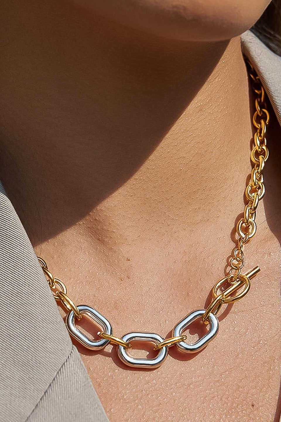 Gold chain necklace worn by a person against a neutral background