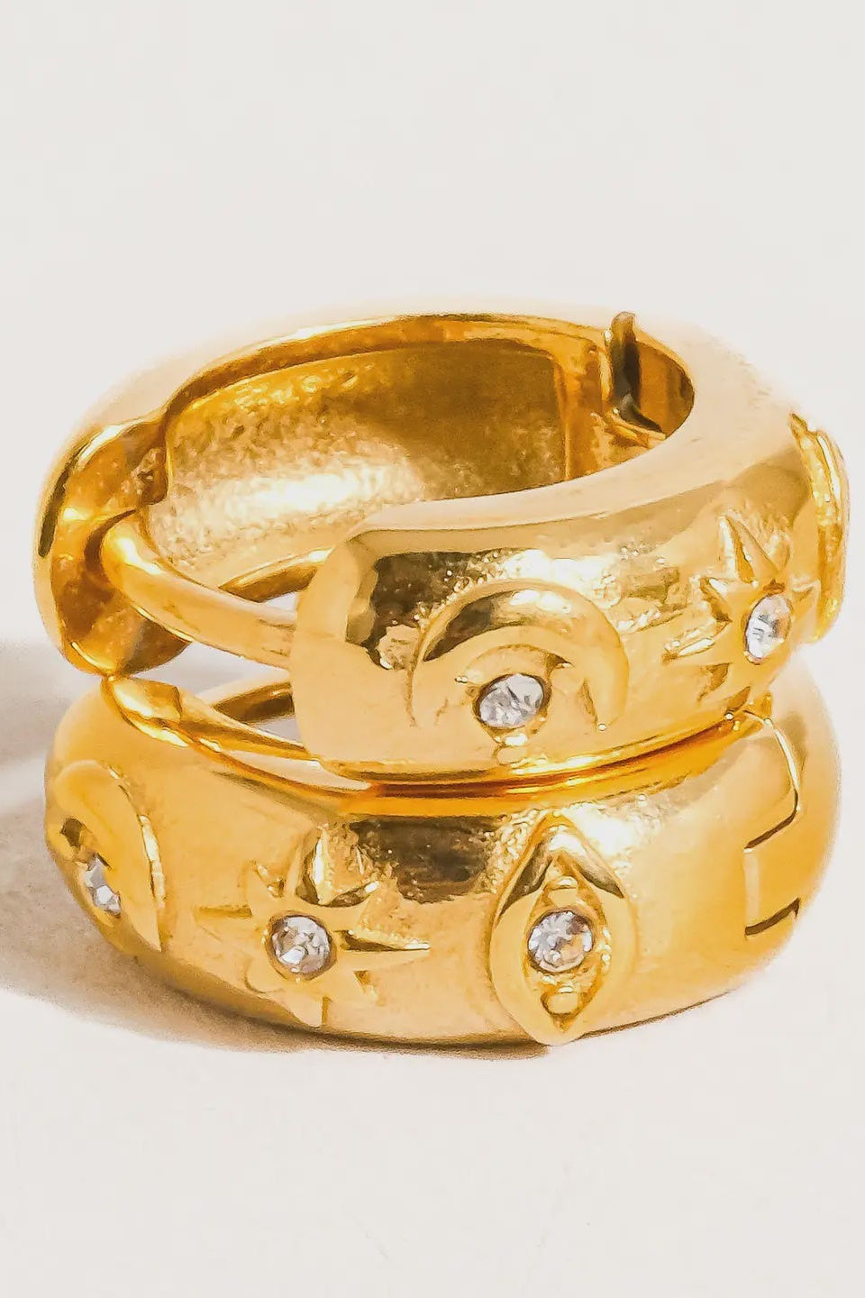 Gold ring with intricate design and embedded diamonds on a light background