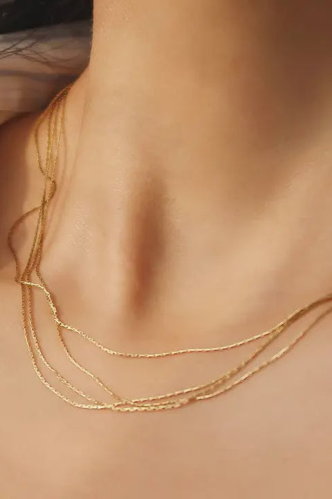 Close-up of a gold necklace on a person's neck with a blurred background