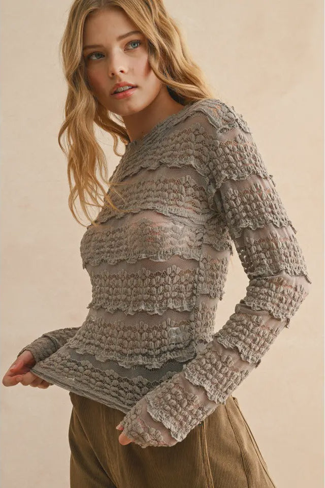Woman wearing a textured gray sweater against a beige background