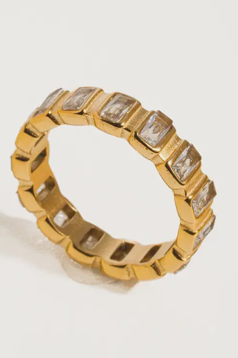 Gold ring with embedded diamonds on a light gray background