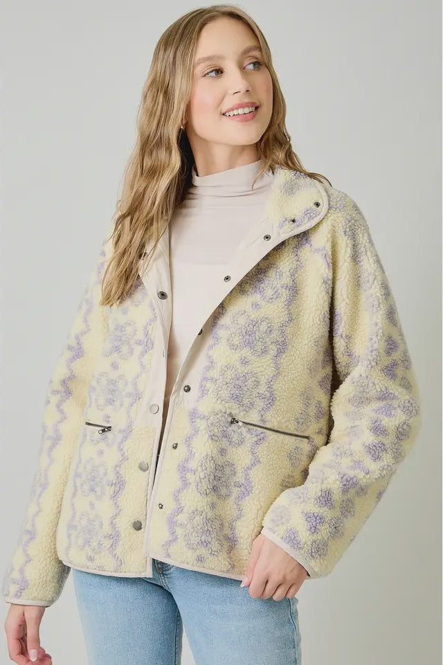 Woman wearing a patterned yellow jacket on a plain background