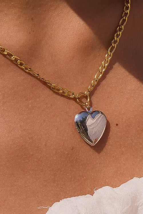 Gold chain necklace with a heart-shaped pendant on a skin-toned background