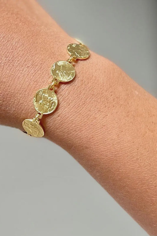 Gold bracelet on a wrist with a blurred background