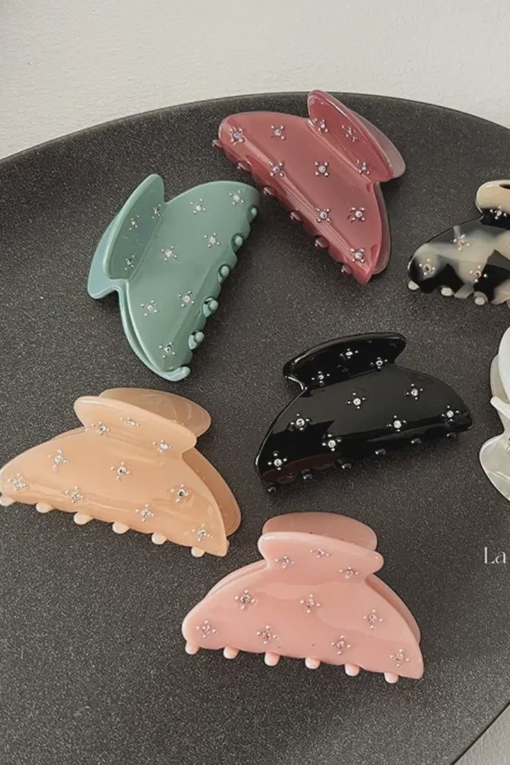 Set of colorful hair clips on a dark surface with a light gray background.