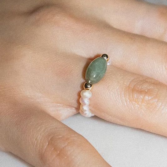 ring with freshwater pearl and 2 gold tone beads with a green colored oblong stone at the center