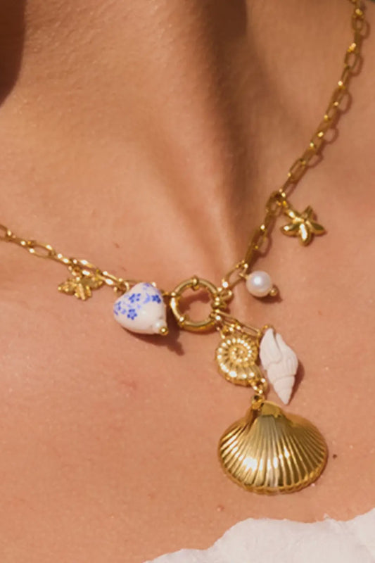 gold mixed charm necklace with ceramic heart, gold charms, and shells.