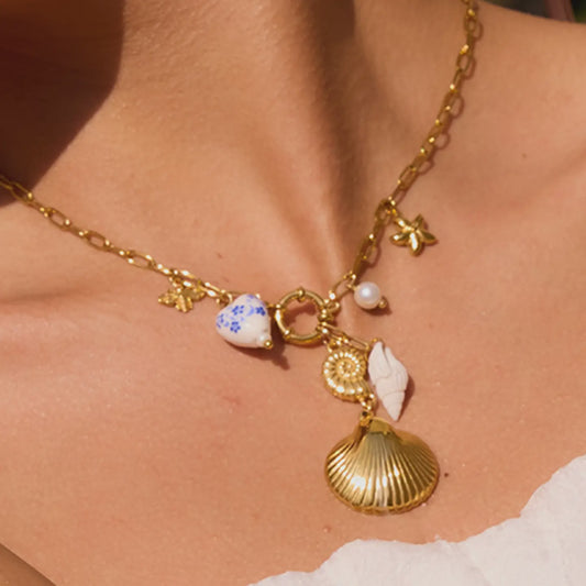 gold mixed charm necklace with ceramic heart, gold charms, and shells. 
