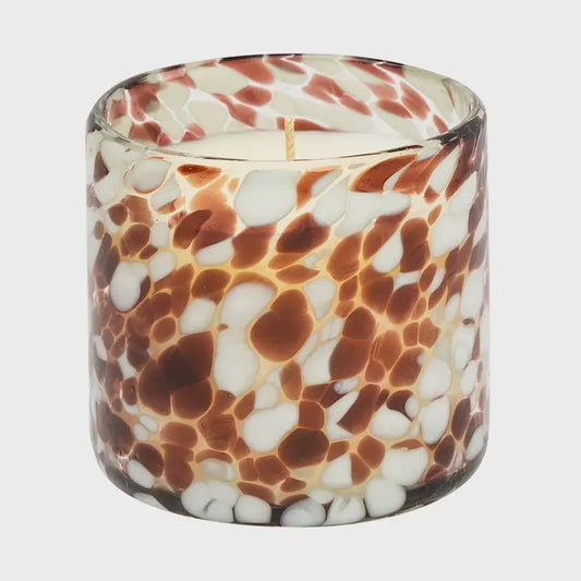 Candle in a glass holder with brown and white marbled pattern on a light gray background