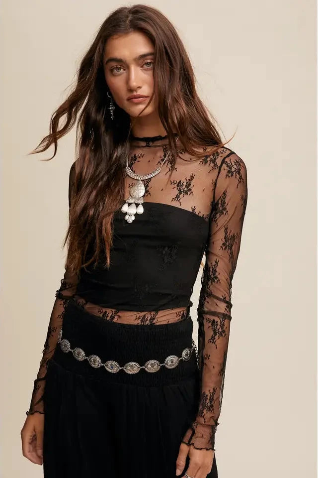 Woman wearing a black lace top with long sleeves on a beige background