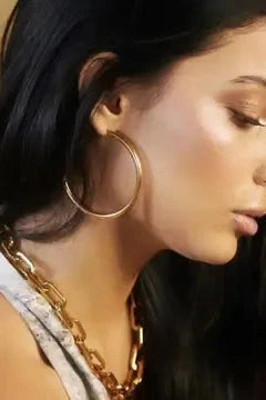 Close-up of a woman wearing gold hoop earrings and necklace.