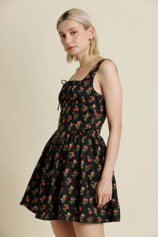 Woman wearing a black floral dress against a beige background
