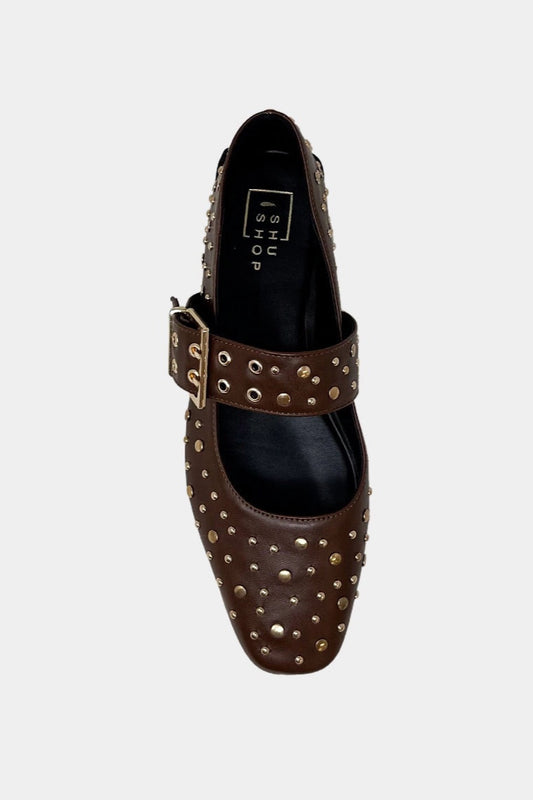 Brown studded flat shoe with a buckle on a white background