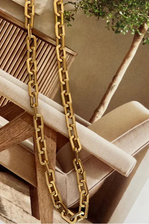 Gold chain necklace on a wooden surface with a blurred background