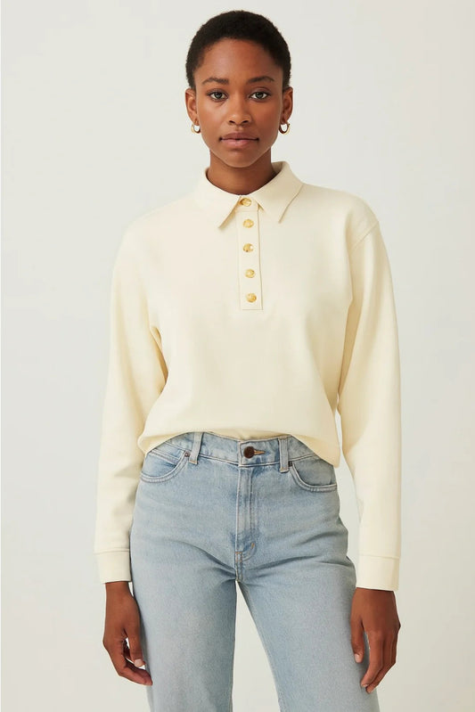 Woman wearing a cream sweater and light blue jeans against a white background