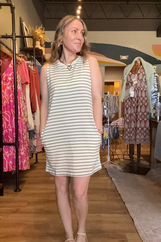Woman trying on a striped dress in a fitting room with mirrors.