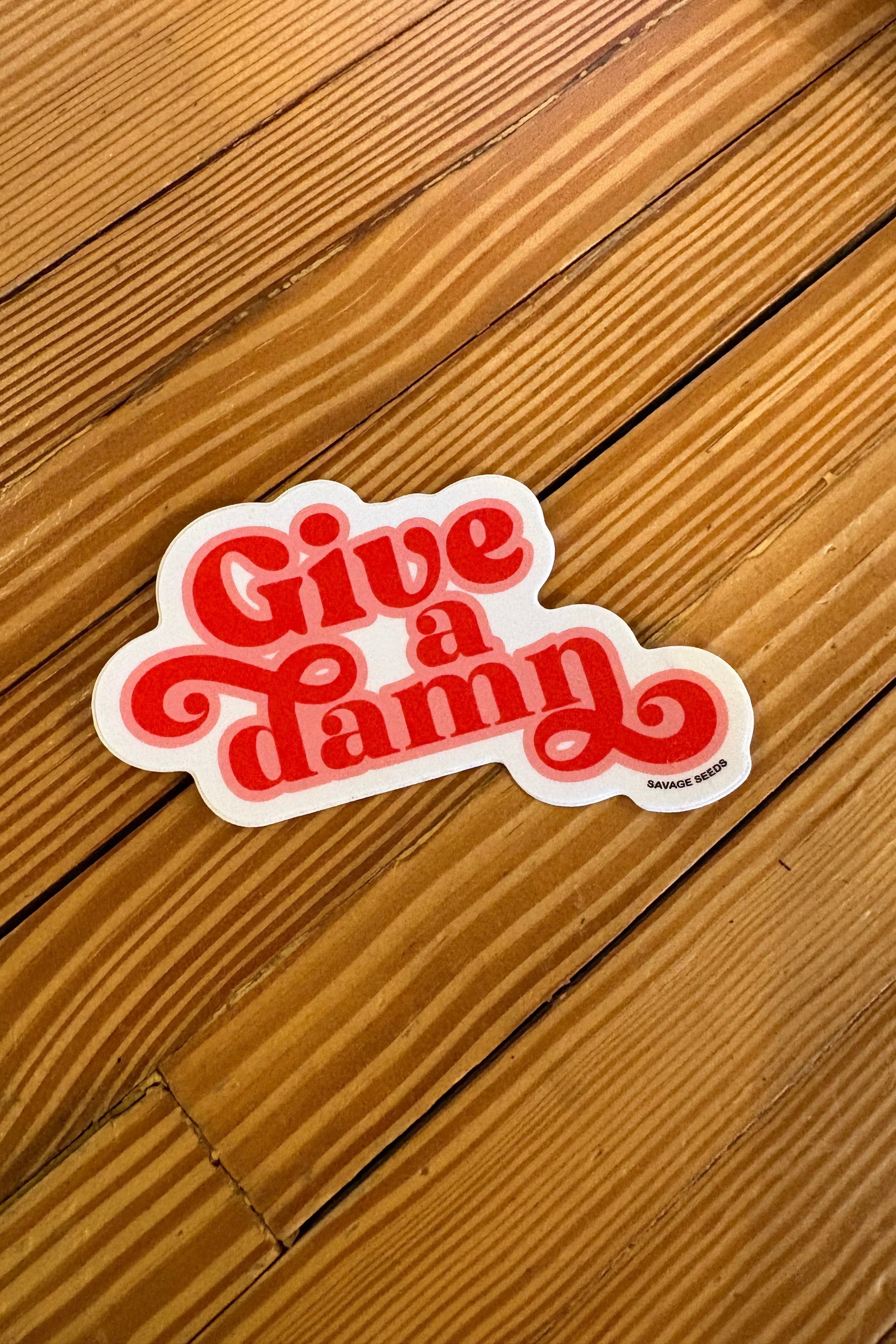 Sticker with 'Give a damn' text on a wooden surface