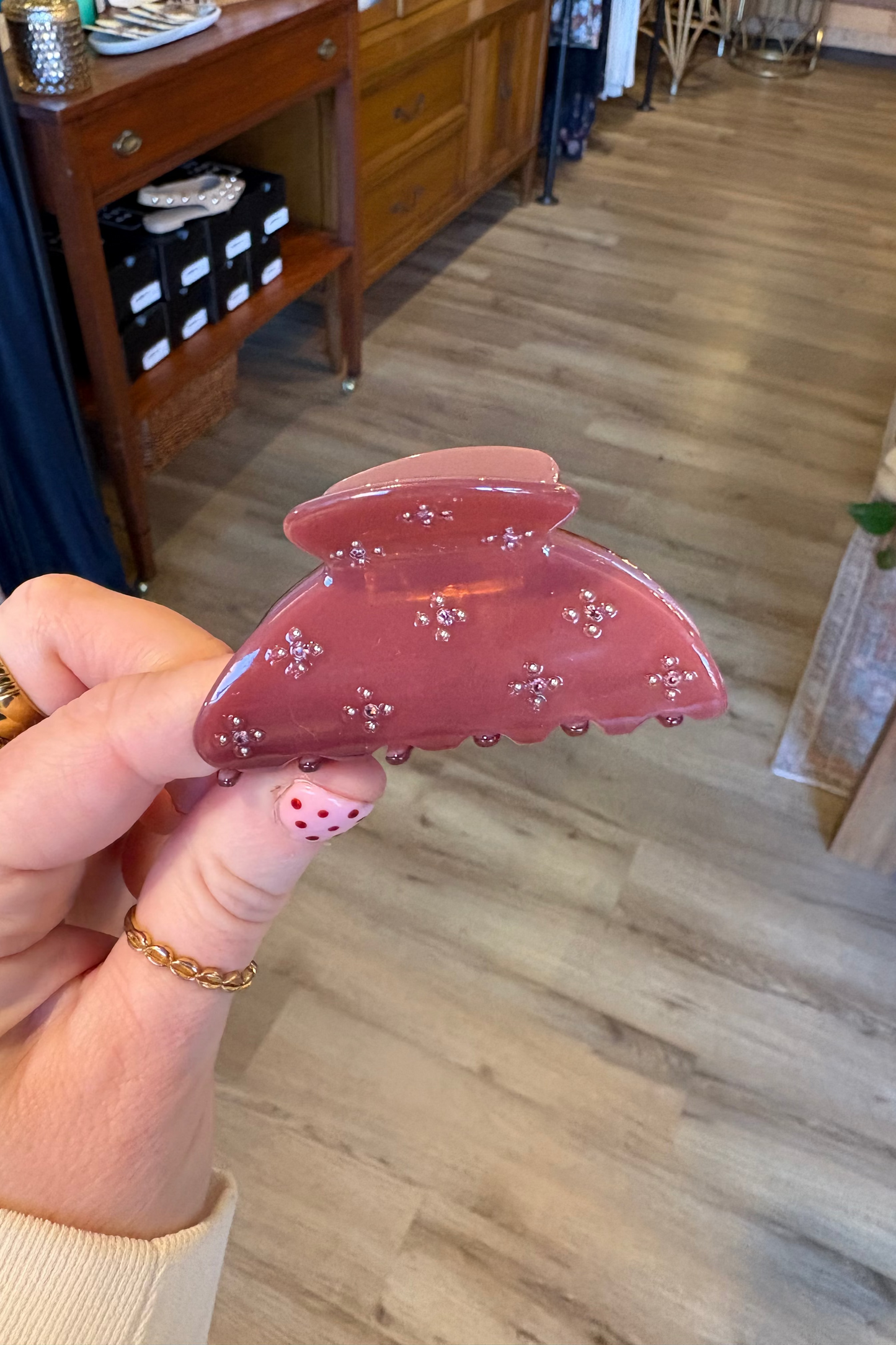 Hand holding a pink hair clip with a blurred indoor background