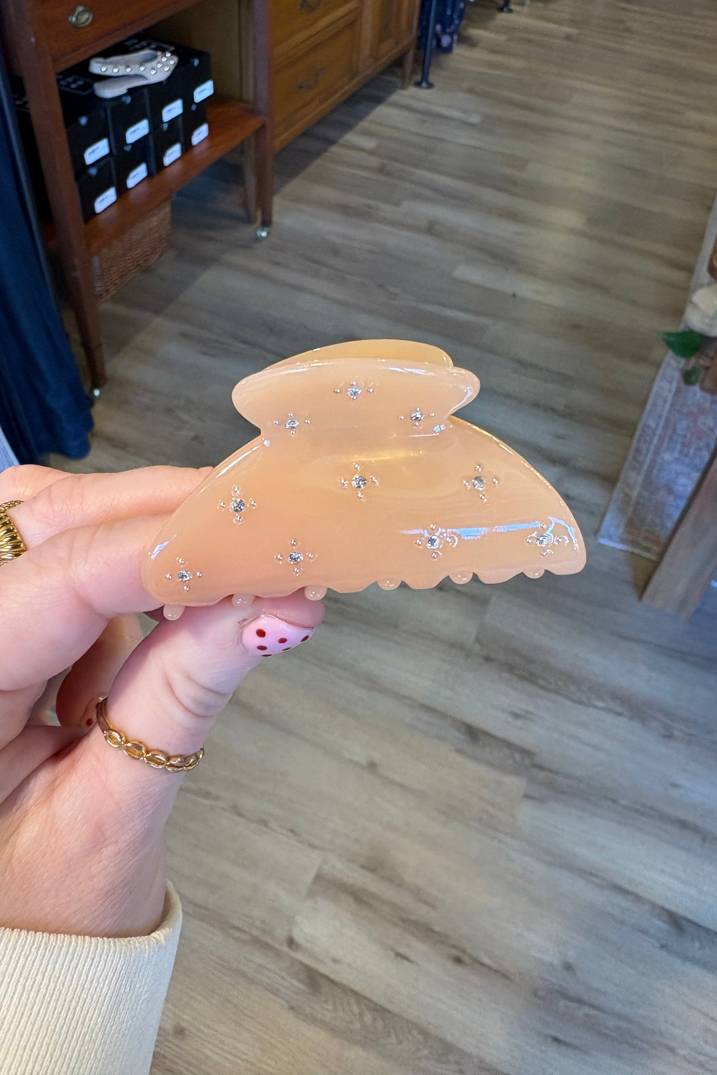 Hand holding a decorative hair clip with a blurred indoor background