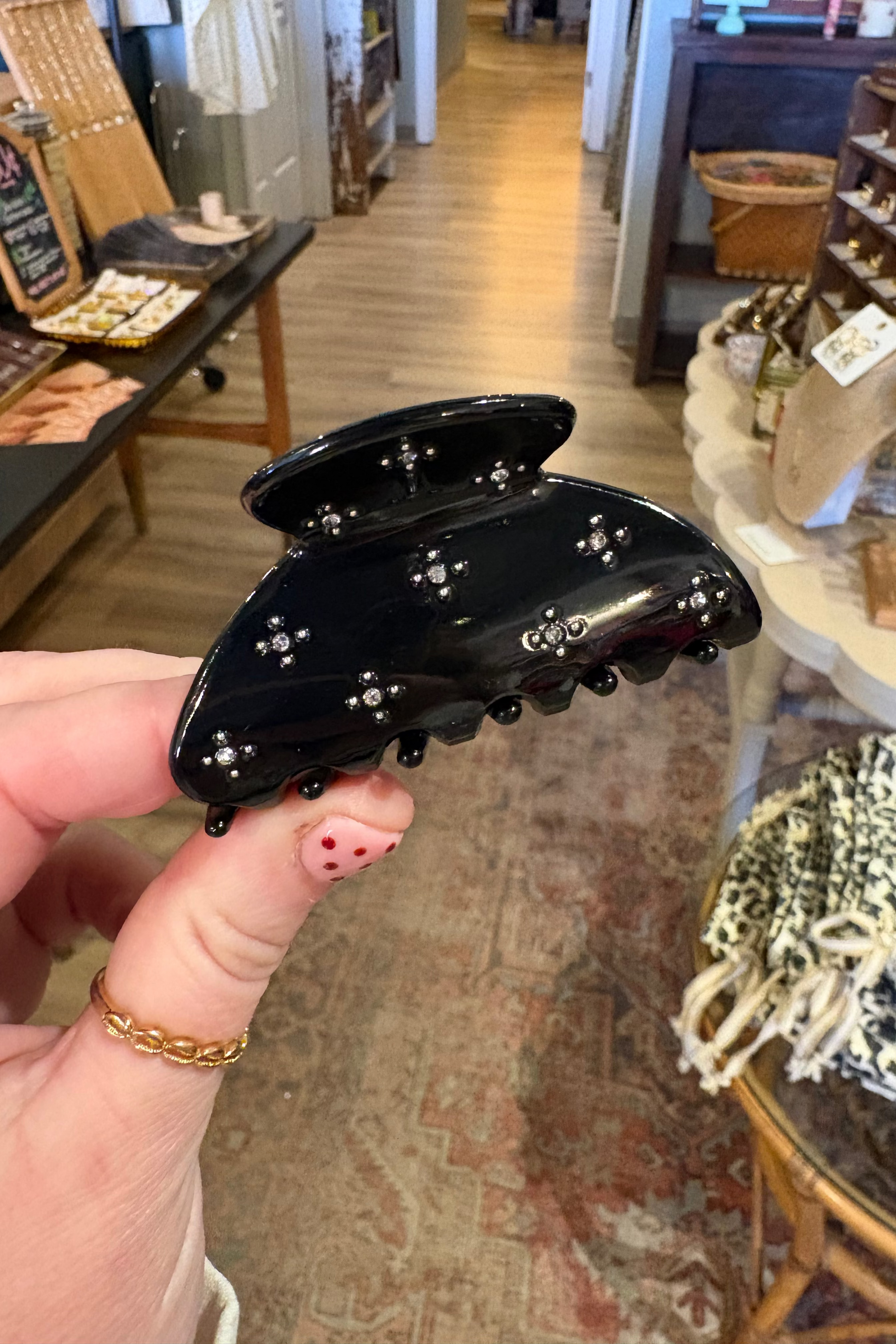 Black hair clip held by a hand in a store setting