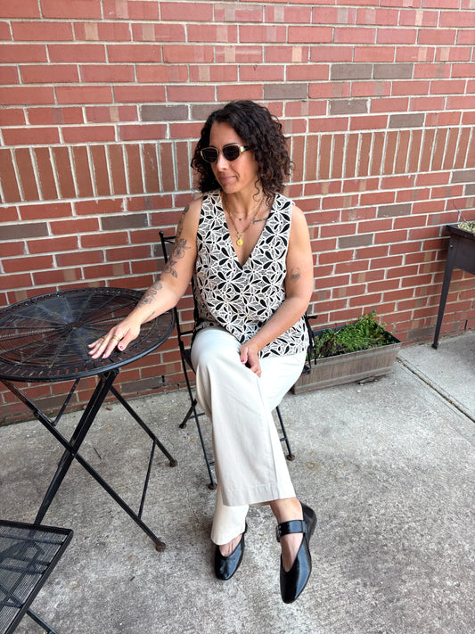 Woman sitting at a small round table outdoors against a brick wall.