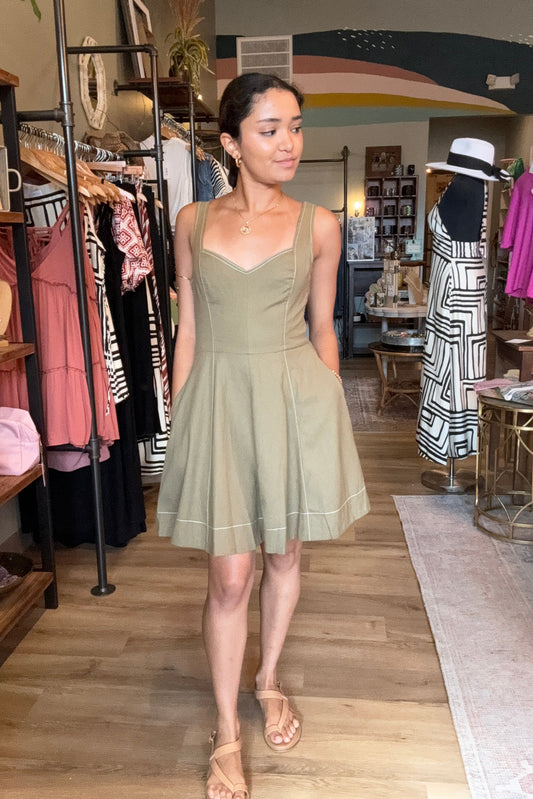 Woman wearing a green dress standing in a room with furniture and decor.