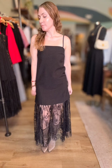 Woman wearing a black dress with lace details in a clothing store.