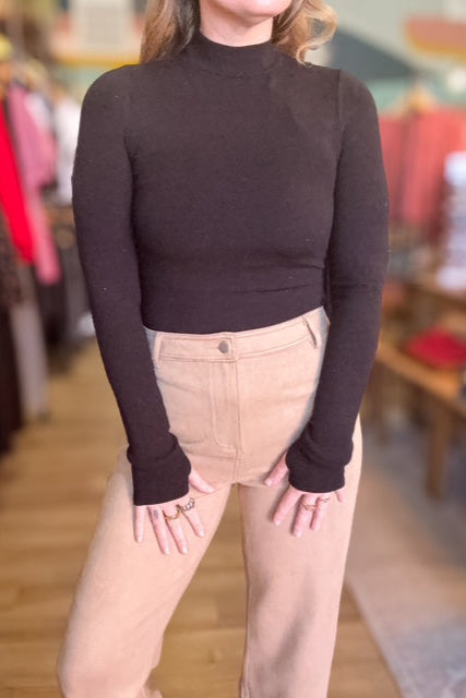 Person wearing a brown turtleneck and beige pants in a store setting