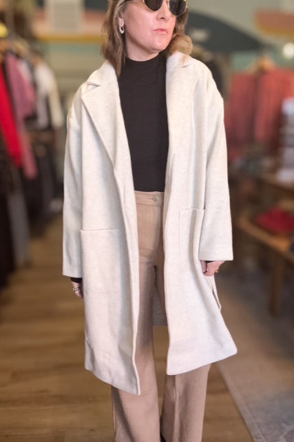 Person wearing a white coat in a clothing store setting