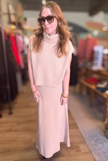 Woman wearing a light pink sleeveless top and skirt in a store setting
