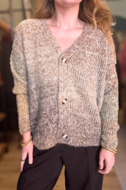 Person wearing a textured beige cardigan with a blurred background