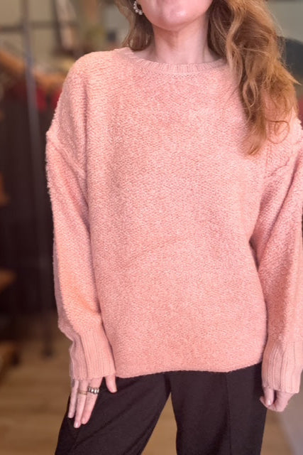 Person wearing a pink sweater with a blurred background