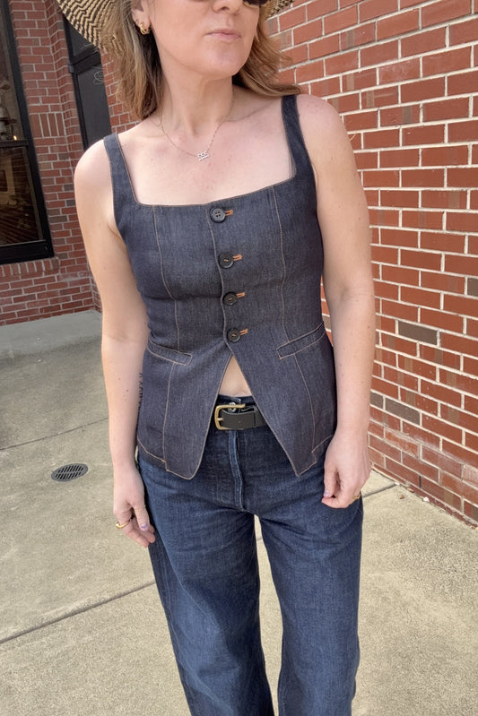 Woman wearing a denim outfit standing against a brick wall.