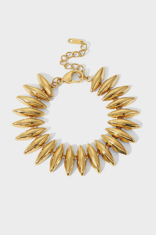 Gold bracelet with spike-like design on a white background