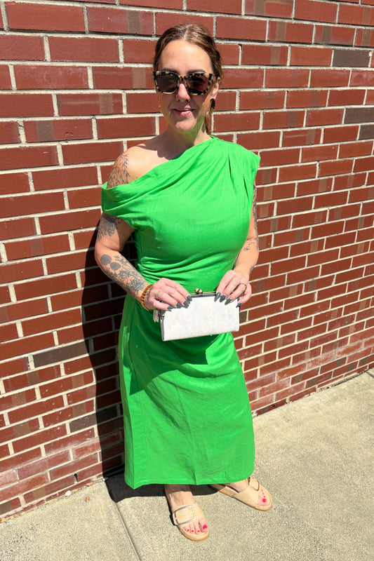 Person wearing a green dress standing on a brick pavement.