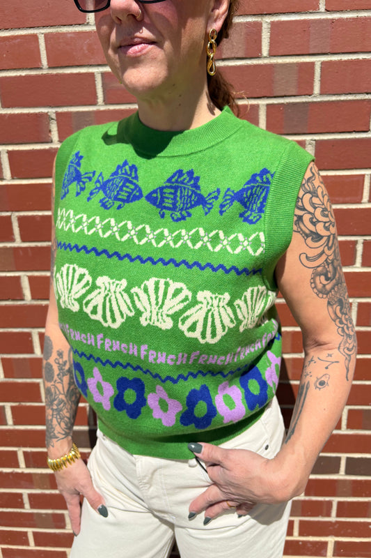 Person wearing a green patterned shirt against a brick wall.