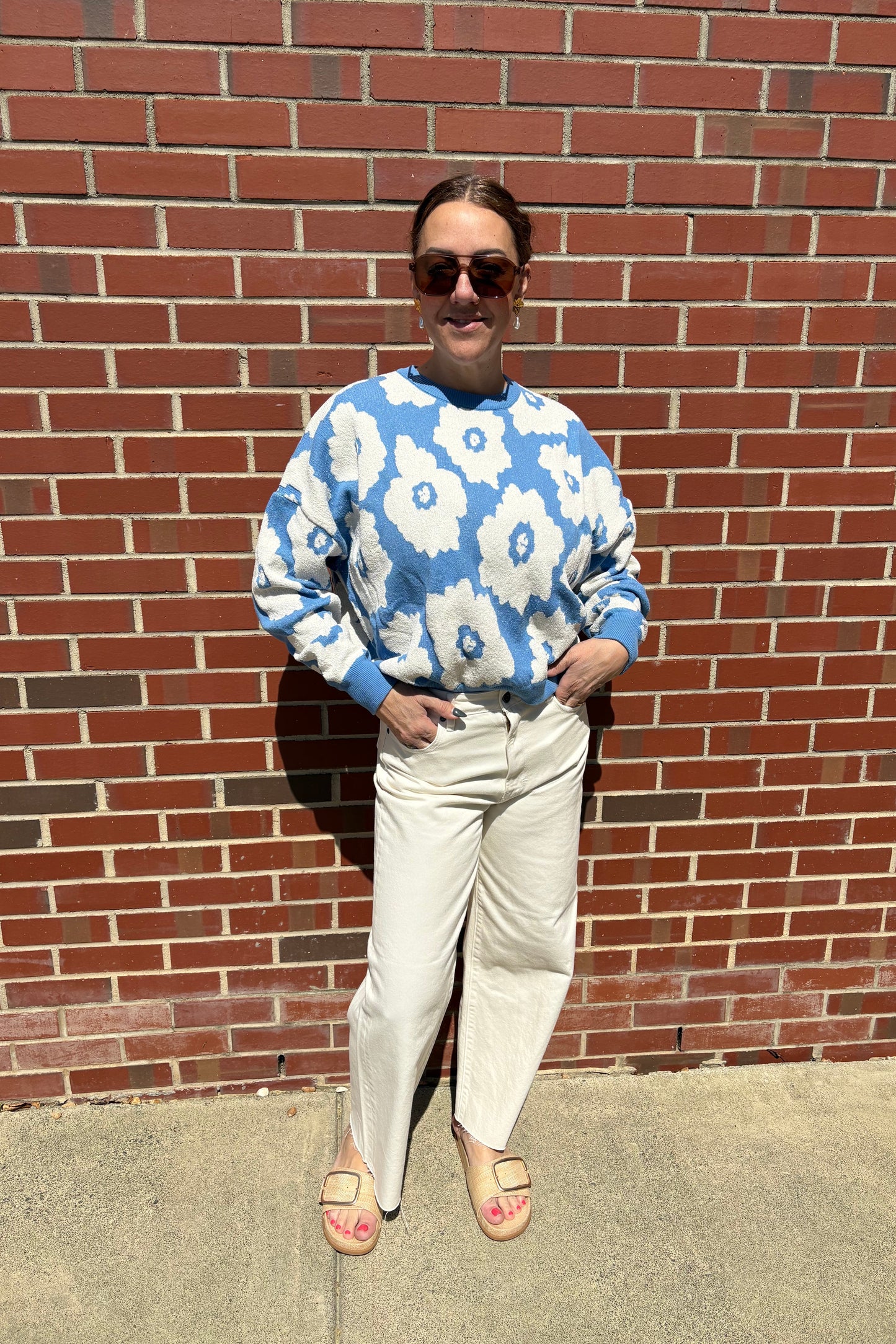 Person wearing a blue floral shirt on a brick sidewalk