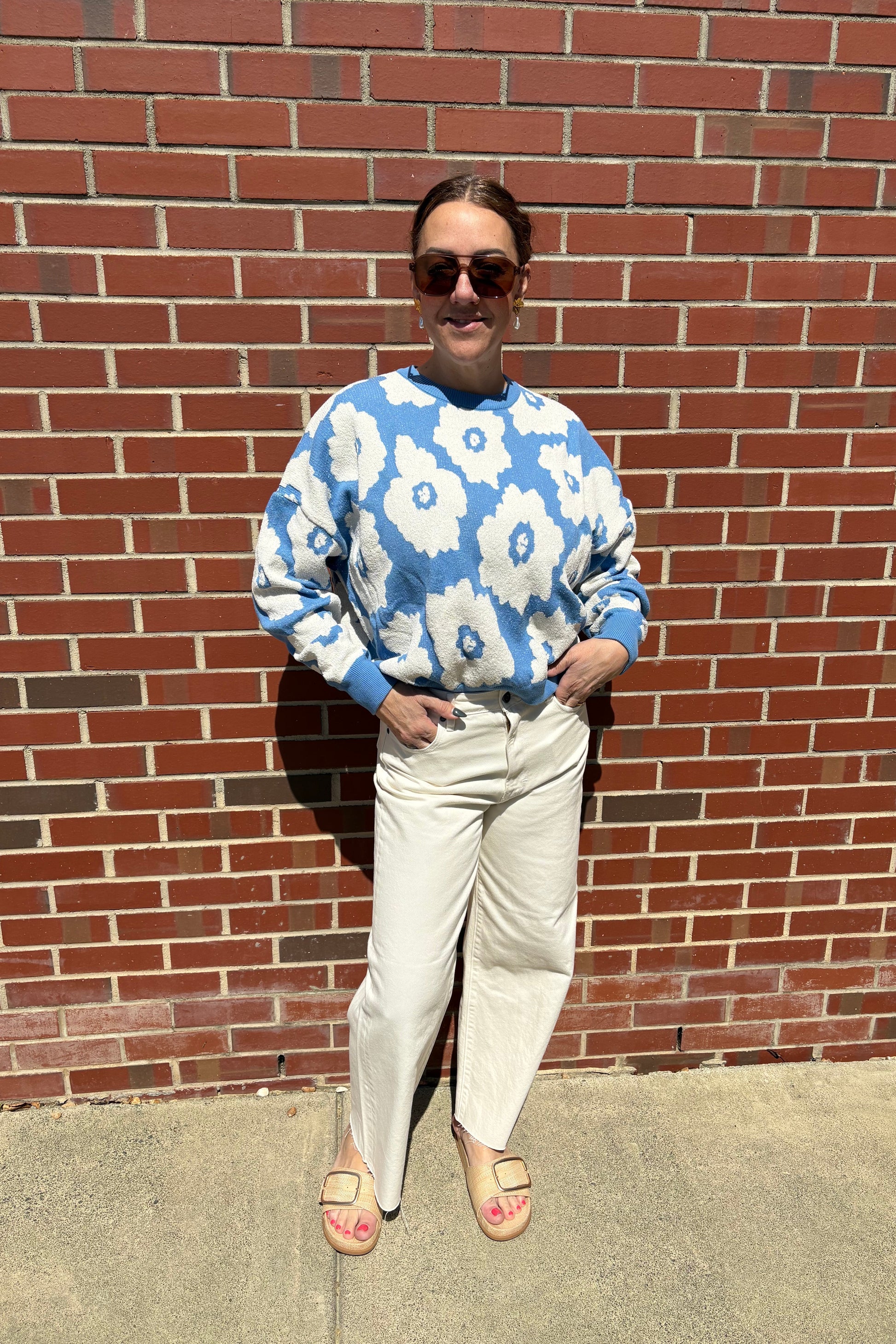 Person wearing a blue floral shirt on a brick sidewalk