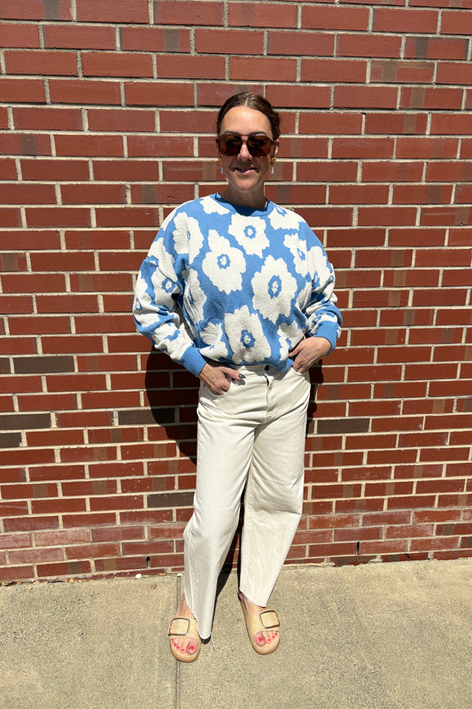 Person wearing a blue floral shirt on a brick sidewalk