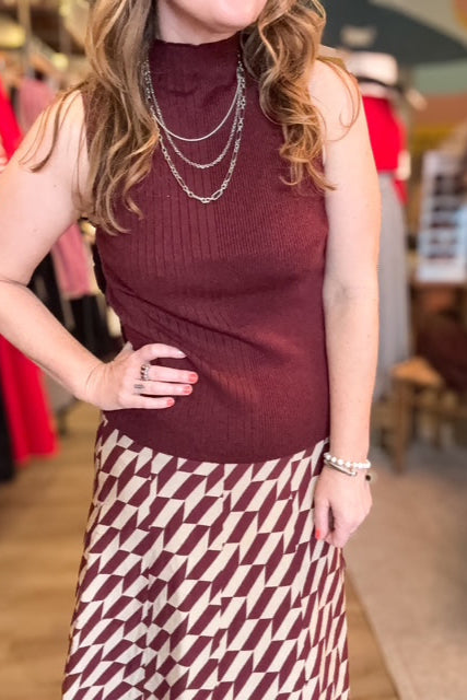Person wearing a maroon sleeveless top and patterned skirt in a store setting