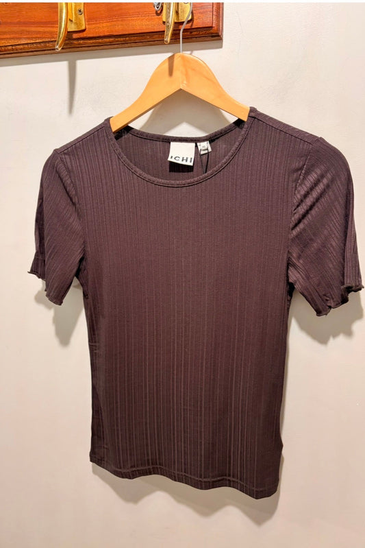 A short-sleeve ribbed knit t-shirt in a dark plum purple color, hanging on a wooden hanger against a plain off-white wall.