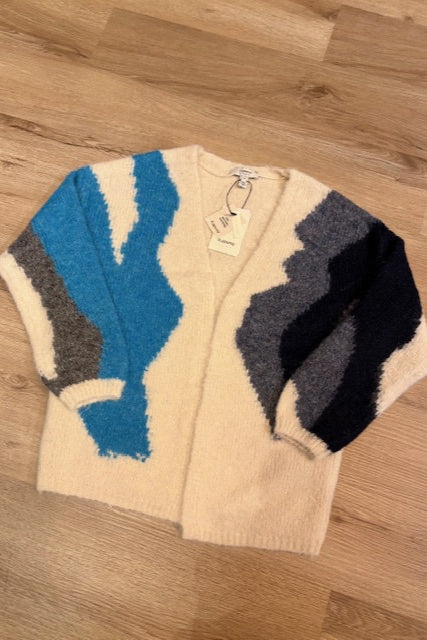 Beige sweater with blue and black abstract patterns on a wooden surface