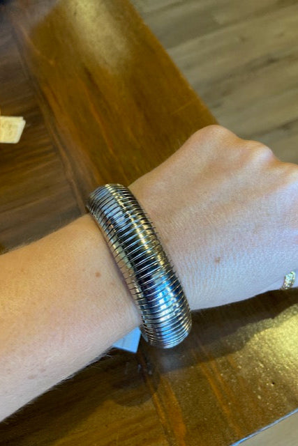 Silver bangle on a wrist with a wooden background