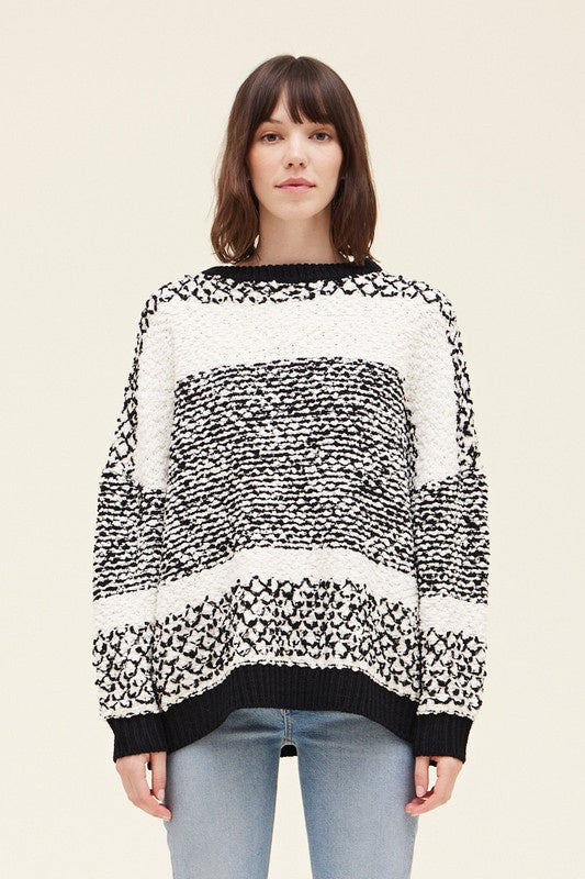 Person wearing a black and white patterned sweater on a beige background