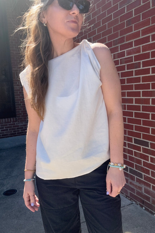 Person lying on a brick pavement wearing a white top and black pants.
