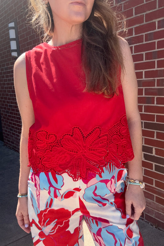 Person wearing a red top with lace details and a floral dress.
